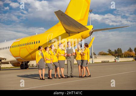 Les employés des compagnies aériennes se tenant près d'un avion jaune à l'aérodrome Banque D'Images