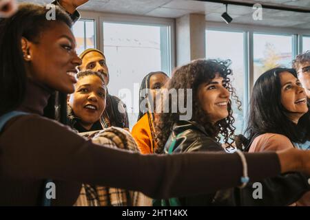 Des étudiants multiraciaux souriants qui vérifient les résultats des tests ensemble à l'université Banque D'Images