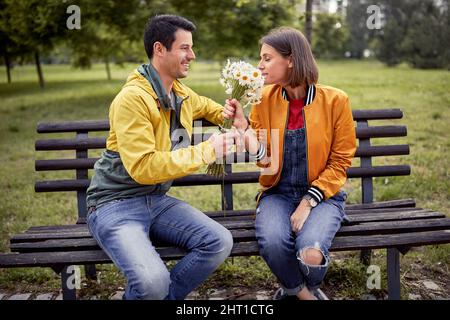 Homme donnant un bouquet de fleurs à une femme dans un parc; concept de couple heureux Banque D'Images