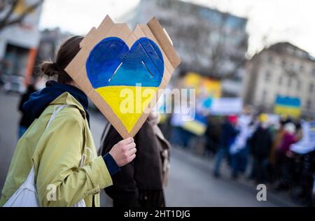 Stuttgart, Allemagne. 26th févr. 2022. Lors d'une manifestation contre le déploiement militaire de la Russie en Ukraine, une femme sur Wilhelmsplatz tient un panneau avec un coeur dans les couleurs de l'Ukraine dans sa main. Credit: Christoph Schmidt/dpa/Alay Live News Banque D'Images