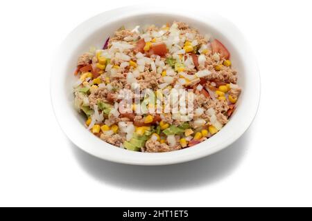 Salade mélangée dans un bol blanc. Ingrédients laitue, maïs, avocat, oignon, thon, tomates, œufs, huile d'olive, chou rouge. Concept alimentaire méditerranéen. Banque D'Images