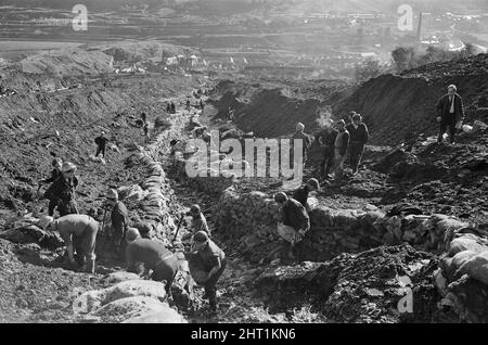 Aberfan - 21st octobre 1966 Services d'urgence et mineurs, sur la colline d'où la boue s'est glissée. Vu ici avec des sacs de sable, construit comme un mur pour endiguer le lent de tout autre toboggan de boue. La ville d'Aberfan et l'école Pantansa Junior sont vues en arrière-plan, dans la vallée en dessous. Le désastre d'Aberfan a été l'effondrement catastrophique d'un pourboire de collierie dans le village gallois d'Aberfan, près de Merthyr Tydfil. Elle a été causée par une accumulation d'eau dans la roche accumulée et le schiste, qui a soudainement commencé à glisser en descente sous forme de lisier et a englouti la Pantglas Junior School en bas, sur Banque D'Images