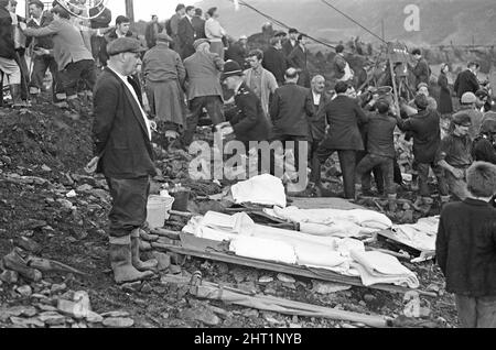 Aberfan - 21st octobre 1966 les hommes locaux et les services d'urgence creusent à la hâte dans la boue pour les survivants de la Pantans Junior School. Un homme étudie la scène de sauvetage, avant de rejoindre les efforts. Le désastre d'Aberfan a été l'effondrement catastrophique d'un pourboire de collierie dans le village gallois d'Aberfan, près de Merthyr Tydfil. Elle a été causée par une accumulation d'eau dans la roche accumulée et le schiste, qui a soudainement commencé à glisser en descente sous forme de lisier et a englouti la Pantglas Junior School ci-dessous, le 21st octobre 1966, tuant 116 enfants et 28 adultes. Le site d'école original est n Banque D'Images