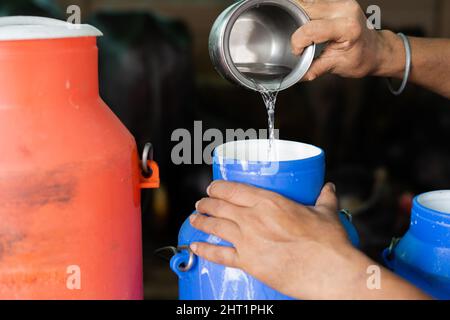 Gros plan, lait producteur laitier mélangeant de l'eau dans le réservoir de lait à la ferme - conept de lait d'adultération, et de contamination. Banque D'Images
