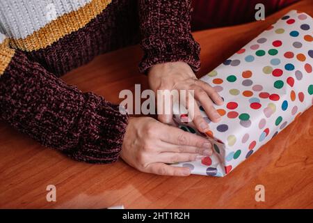 Femme emballant un cadeau de Noël. Une femme méconnaissable empaquetage et décorant un cadeau de Noël. Concept de Noël et de fête des mères Banque D'Images