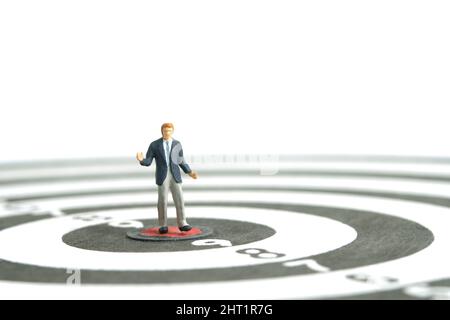 Photographie miniature de personnage de jouet de personnes. Un homme d'affaires haussant debout au centre du dartboard. Isolé sur fond blanc. Photo d'image Banque D'Images