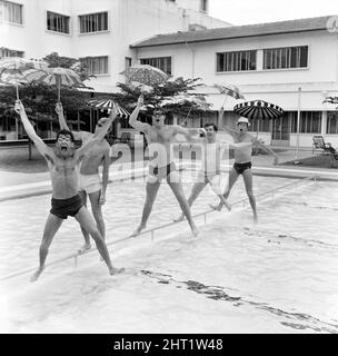 Freddie, groupe pop de Manchester, et les Rêveurs photographiés à Singapour lors de leur tournée mondiale. Ici, le groupe dirigé par le chanteur Freddie Garrity est photographié avec des parasols dans la piscine de l'hôtel. 30th mars 1965. Banque D'Images