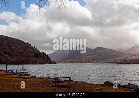 Les sommets enneigés et couverts de nuages des montagnes accidentées du parc national de Snowdonia, vus de l'aire de pique-nique au bord du lac à CEI Llydan Banque D'Images