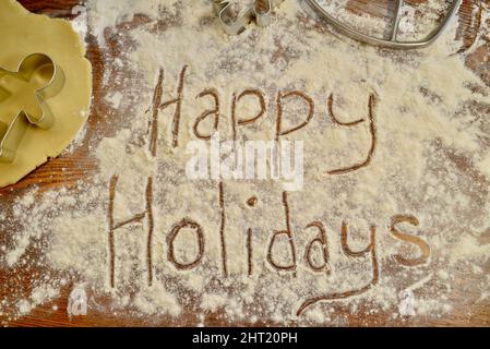Happy Holidays écrit du texte dans la farine, sur le comptoir, avec emporte-pièce en métal pour pain d'épice, pour la cuisson des biscuits de Noël, Browntown, Wisconsin USA Banque D'Images