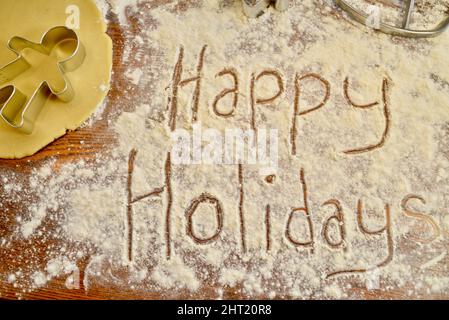 Happy Holidays écrit du texte dans la farine, sur le comptoir, avec emporte-pièce en métal pour pain d'épice, pour la cuisson des biscuits de Noël, Browntown, Wisconsin USA Banque D'Images