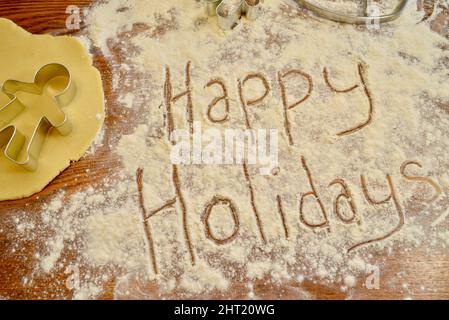 Happy Holidays écrit du texte dans la farine, sur le comptoir, avec emporte-pièce en métal pour pain d'épice, pour la cuisson des biscuits de Noël, Browntown, Wisconsin USA Banque D'Images