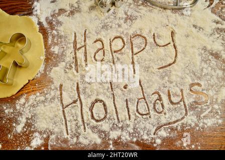 Happy Holidays écrit du texte dans la farine, sur le comptoir, avec emporte-pièce en métal pour pain d'épice, pour la cuisson des biscuits de Noël, Browntown, Wisconsin USA Banque D'Images