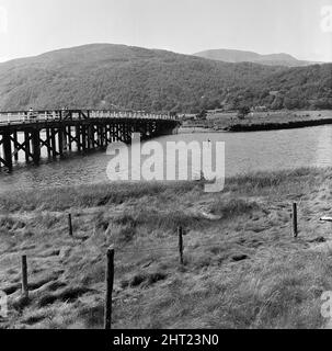 Le bateau de plaisance Prince of Wales a chaviré et a fait passer ses 39 passagers dans l'estuaire du Mawddach à Penmaenpool, Merioneth, au nord du pays de Galles, le 22nd juillet 1966 . La visite de l'après-midi d'été est devenue une lutte soudaine pour la survie alors que le bateau faisait un virage en « U » vers une jetée d'atterrissage. Le prince de Galles a été balayé contre un pont à péage. Un trou a été déchiré dans le bateau et il a coulé en trois minutes. Entraînant la mort de 15 personnes, dont 4 enfants. Sur la photo, au milieu de l'image, la pointe du mât du bateau de plaisance, et à gauche le pont à péage dans lequel le bateau s'est écrasé avant lui Banque D'Images