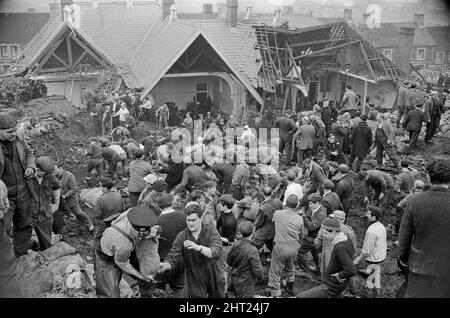 Aberfan - 21st octobre 1966 les hommes locaux et les services d'urgence creusent à la hâte dans la boue pour les survivants de la Pantans Junior School. Ils forment des lignes pour déplacer des seaux de boue, d'un à l'autre, loin de la scène. Et pour être en ligne, en se déplaçant vers le haut de la file d'attente pour leur tour à creuser. Deux hommes vus avec un sac de sable rempli, plein de boue, qui a été utilisé pour faire un mur en cas de glissement de terrain ultérieur. Le désastre d'Aberfan a été l'effondrement catastrophique d'un pourboire de collierie dans le village gallois d'Aberfan, près de Merthyr Tydfil. Elle a été causée par une accumulation d'eau dans le rocher et le schiste accumulés Banque D'Images