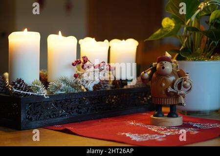 Gros plan de la petite figure d'homme en bois devant les bougies de Noël. Banque D'Images