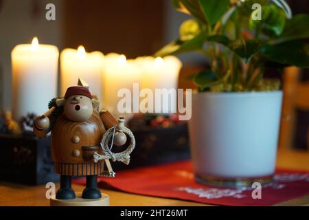 Gros plan de la petite figure d'homme en bois devant les bougies de Noël. Banque D'Images