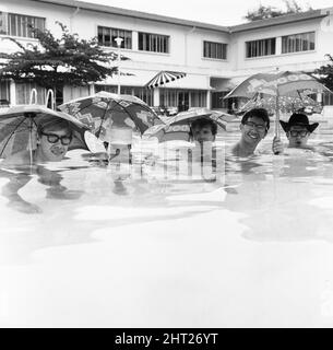 Freddie, groupe pop de Manchester, et les Rêveurs photographiés à Singapour lors de leur tournée mondiale. Ici, le groupe dirigé par le chanteur Freddie Garrity est photographié avec des parasols dans la piscine de l'hôtel. 30th mars 1965. Banque D'Images