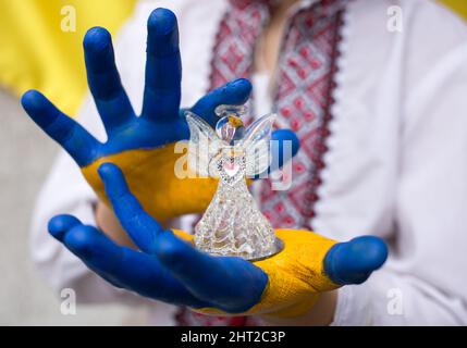 les mains des enfants, peintes en jaune et bleu, tiennent un ange de verre. Les enfants contre la guerre. L'invasion de l'Ukraine par la Russie, une demande d'aide de la coopération mondiale Banque D'Images