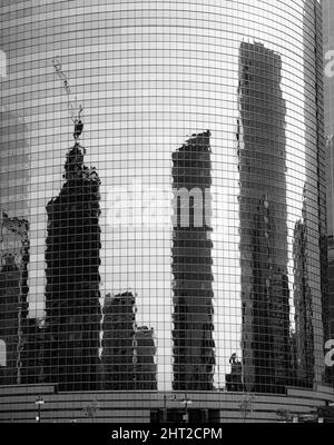 Vue verticale en niveaux de gris d'un bâtiment moderne en verre reflétant d'autres grands bâtiments Banque D'Images