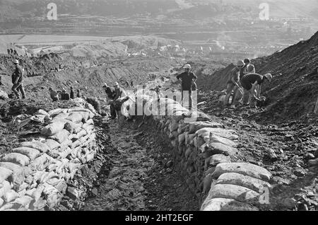 Aberfan - 21st octobre 1966 Services d'urgence et mineurs, sur la colline d'où la boue s'est glissée. Vu ici avec des sacs de sable, construit comme un mur pour endiguer le lent de tout autre toboggan de boue. La ville d'Aberfan et l'école Pantansa Junior sont vues en arrière-plan, dans la vallée en dessous. Le désastre d'Aberfan a été l'effondrement catastrophique d'un pourboire de collierie dans le village gallois d'Aberfan, près de Merthyr Tydfil. Elle a été causée par une accumulation d'eau dans la roche accumulée et le schiste, qui a soudainement commencé à glisser en descente sous forme de lisier et a englouti la Pantglas Junior School en bas, sur Banque D'Images