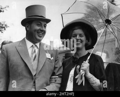 Doug Ellis, agent de voyage de Birmingham, SunFlight, en photo avec sa femme Heidi Marie Kroeger au champ de courses d'Ascot, Royal Ascot, Hunt Cup Day, mercredi 16th juin 1965. Notre photo montre ... Mme Ellis portant un chapeau et un manteau noirs, portant un parasol transparent. Banque D'Images