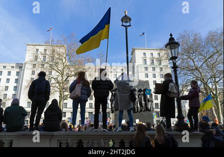 Protestation contre l'invasion russe de l'Ukraine devant Downing Street. Les manifestants debout en silhouette agitant un drapeau ukrainien. Londres Banque D'Images