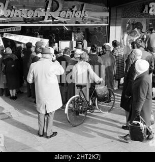 Les acheteurs regardent les funérailles d'État de Sir Winston Churchill par la vitrine de Robinson Rentals, Coventry, 30th janvier 1965. Banque D'Images