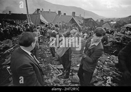 Aberfan - 21st octobre 1966 les hommes locaux et les services d'urgence creusent à la hâte dans la boue pour les survivants de la Pantans Junior School. Ils forment des lignes pour déplacer des seaux de boue, d'un à l'autre, loin de la scène. Et pour être en ligne, en se déplaçant vers le haut de la file d'attente pour leur tour à creuser. Le désastre d'Aberfan a été l'effondrement catastrophique d'un pourboire de collierie dans le village gallois d'Aberfan, près de Merthyr Tydfil. Elle a été causée par une accumulation d'eau dans la roche accumulée et le schiste, qui a soudainement commencé à glisser en descente sous forme de lisier et a englouti la Pantans Junior School ci-dessous Banque D'Images