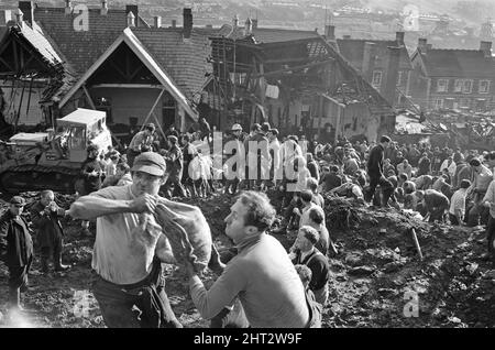 Aberfan - 21st octobre 1966 les hommes locaux et les services d'urgence creusent à la hâte dans la boue pour les survivants de la Pantans Junior School. Ils forment des lignes pour déplacer des seaux de boue, d'un à l'autre, loin de la scène. Et pour être en ligne, en se déplaçant vers le haut de la file d'attente pour leur tour à creuser. Deux hommes vus avec un sac de sable rempli, plein de boue, qui a été utilisé pour faire un mur en cas de glissement de terrain ultérieur. Le désastre d'Aberfan a été l'effondrement catastrophique d'un pourboire de collierie dans le village gallois d'Aberfan, près de Merthyr Tydfil. Elle a été causée par une accumulation d'eau dans le rocher et le schiste accumulés Banque D'Images