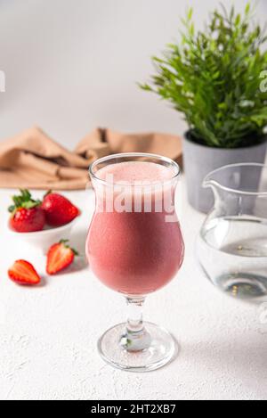 shake aux protéines de fraise dans du verre. fraises crues mélangées à de la poudre de protéine et de l'eau servies dans du verre. baies crues, eau propre, bac de cuisine blanc Banque D'Images