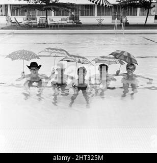 Freddie, groupe pop de Manchester, et les Rêveurs photographiés à Singapour lors de leur tournée mondiale. Ici, le groupe dirigé par le chanteur Freddie Garrity est photographié avec des parasols dans la piscine de l'hôtel. 30th mars 1965. Banque D'Images