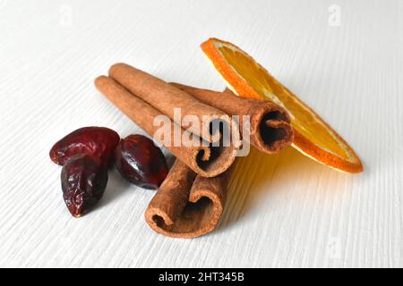 Cannelle, orange séchée et hanches roses séchées sur fond blanc. Banque D'Images