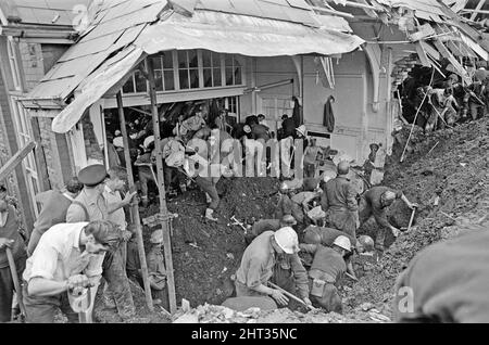 Aberfan - 21st octobre 1966 les hommes locaux et les services d'urgence creusent à la hâte dans la boue pour les survivants de la Pantans Junior School. Le désastre d'Aberfan a été l'effondrement catastrophique d'un pourboire de collierie dans le village gallois d'Aberfan, près de Merthyr Tydfil. Elle a été causée par une accumulation d'eau dans la roche accumulée et le schiste, qui a soudainement commencé à glisser en descente sous forme de lisier et a englouti la Pantglas Junior School ci-dessous, le 21st octobre 1966, tuant 116 enfants et 28 adultes. Le site de l'école d'origine est maintenant un jardin commémoratif. Photo prise le 21st octobre 1966The la veille Banque D'Images