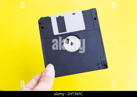 Disquette en main sur fond jaune Banque D'Images