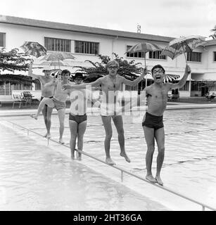 Freddie, groupe pop de Manchester, et les Rêveurs photographiés à Singapour lors de leur tournée mondiale. Ici, le groupe dirigé par le chanteur Freddie Garrity est photographié avec des parasols dans la piscine de l'hôtel. 30th mars 1965. Banque D'Images