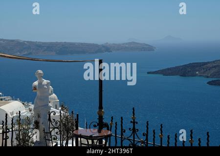 Santorin, Grèce : 10 mai 2021 : vue imprenable depuis une terrasse de restaurants avec tables, chaises et une statue grecque sur la mer Égée à Santorin Banque D'Images