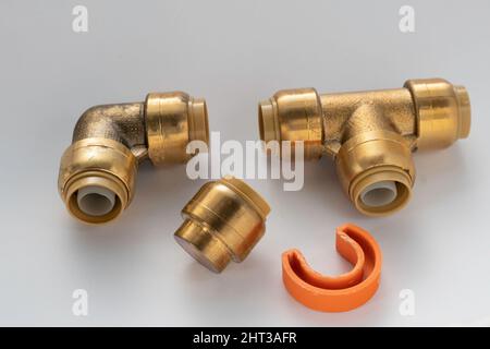 Pièces de plomberie, tuyaux, coudes, coins et bouchons en laiton sur fond blanc Banque D'Images