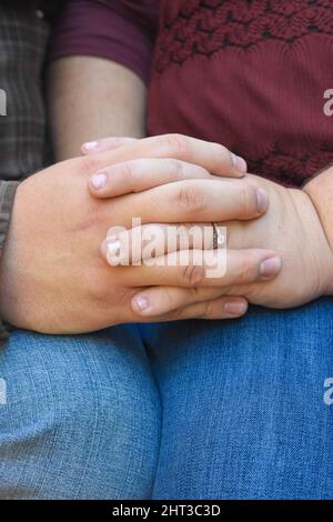 Gros plan des doigts et des mains d'un couple nouvellement engagé reposant sur les genoux. Banque D'Images