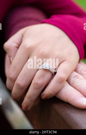 Couple engagé tenant les mains reposant sur le genou. Manches rouges sur les deux couples. Banque D'Images