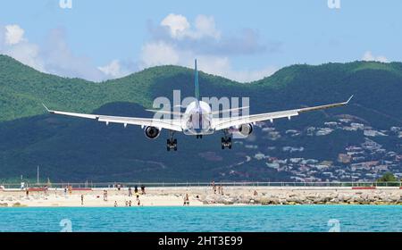 Avion survolant des personnes lors de l'atterrissage à Maho Beach à Saint-Martin à l'aéroport Princess Juliana. Vue unique sur l'atterrissage en avion commercial. Banque D'Images