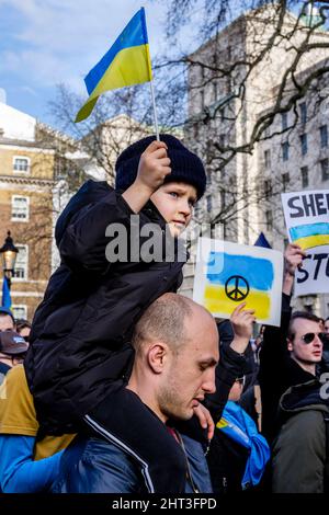 26th février 2022 : des ressortissants ukrainiens et des partisans pro-ukrainiens se rassemblent à Whitehall pour protester contre l'invasion russe de l'Ukraine. Londres, Royaume-Uni. Photo : un jeune garçon est assis sur les épaules de son père, portant un drapeau ukrainien. Banque D'Images