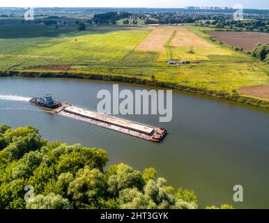 Towboat transporte la barge avec le sable le long de la rivière tranquille Banque D'Images