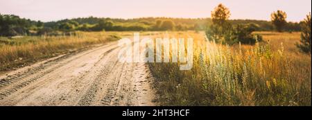 Route de campagne à travers le paysage de champ. Route de campagne en automne Field en soirée ensoleillée Banque D'Images