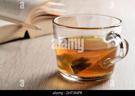 Thé dans une tasse en verre et livre ouvert. Temps de thé. Banque D'Images
