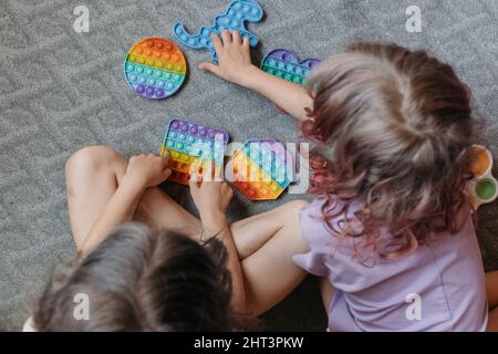 Vue d'en haut jusqu'aux enfants jouant avec des jouets pop IT Banque D'Images