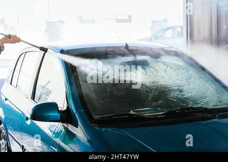 Détail du lavage de l'avant d'une voiture avec un tuyau flexible Banque D'Images