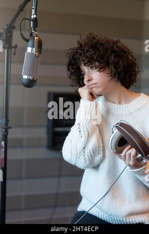 Une jeune chanteuse de cheveux mauriquement s'inquiète dans le studio d'enregistrement Banque D'Images