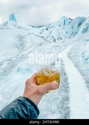 Homme tenant un verre de whisky tout en trekking sur le glacier Perito Moreno en Argentine Banque D'Images