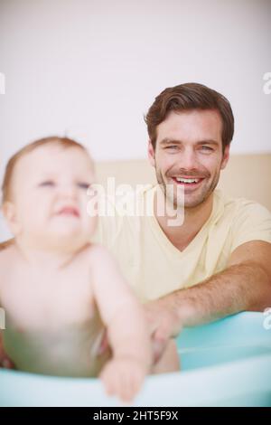 Parfois, elle n'aime pas autant le bain Un jeune père se liant à sa fille au moment du bain. Banque D'Images