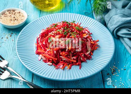 Salade de vitamines avec betteraves, carottes, chou et graines de sésame sur fond bleu. Banque D'Images